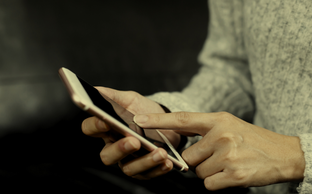 Hands holding a mobile device, suggesting the use of smartphones or tablets for communication or digital tasks.