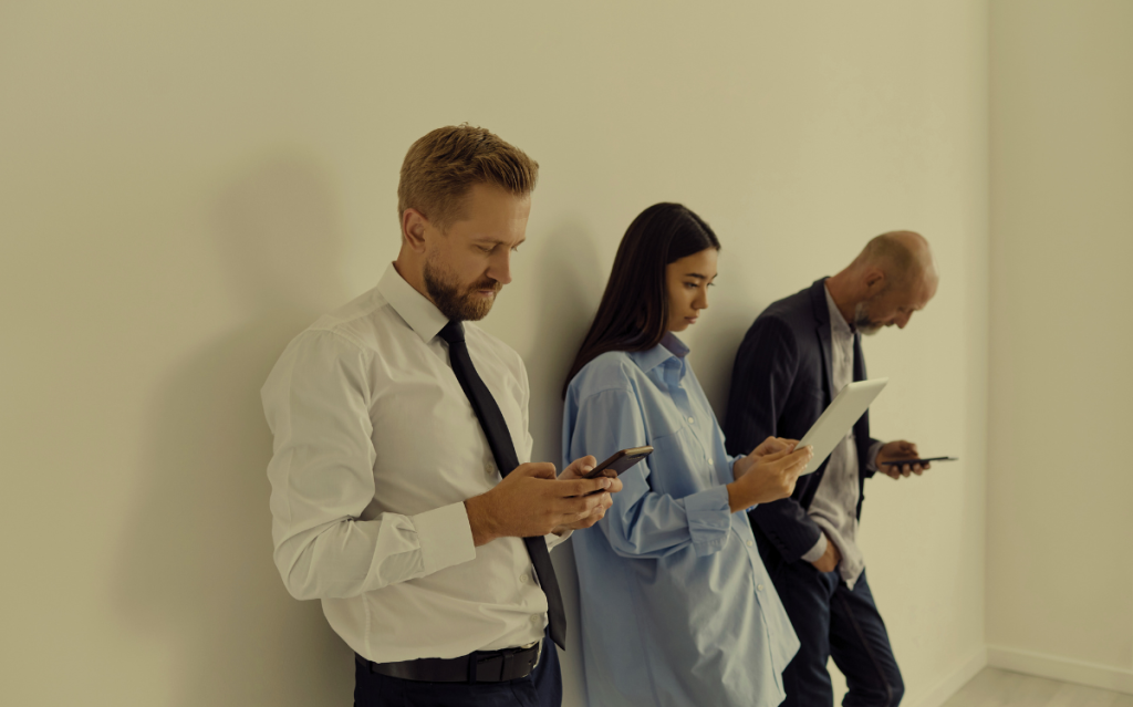 Three professionals in formal attire, each utilizing a mobile device, suggesting the integration of technology in business or office settings.