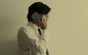 A person in formal attire speaking on a mobile device, suggesting the use of smartphones for professional or business-related communication.
