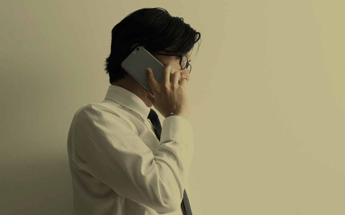 A person in formal attire speaking on a mobile device, suggesting the use of smartphones for professional or business-related communication.